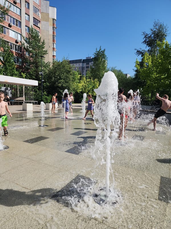 Children play in urban water fountains on sunny morning