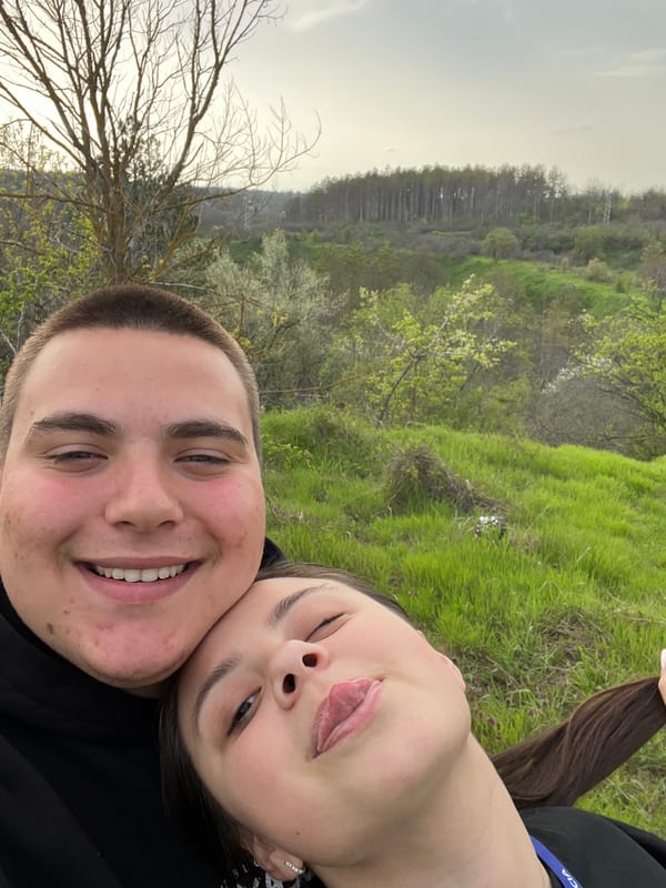 Two people take playful hillside selfie in Pleven