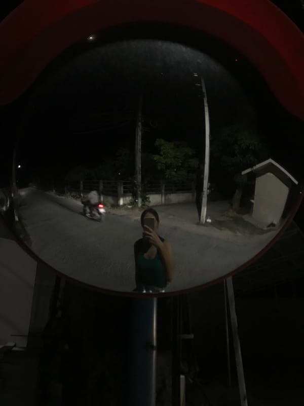 Person reflected in safety mirrors on Thailand street