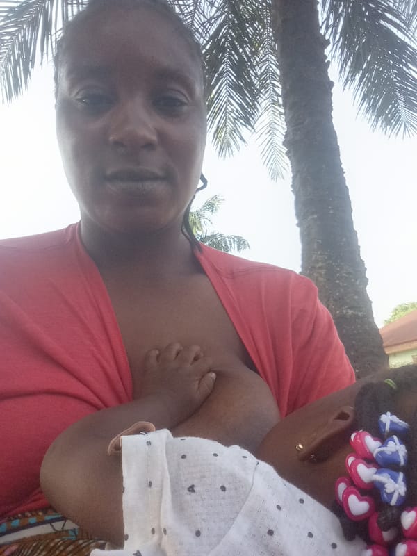 Woman breastfeeds infant outdoors in Akwanga, Nigeria
