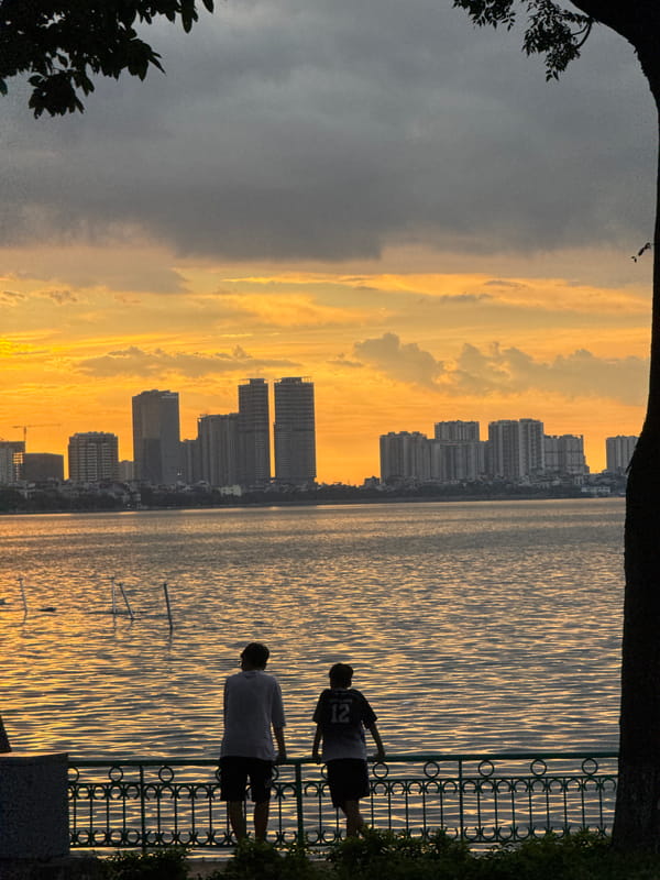 Hanoi lakeside at sunset, silhouettes and still water