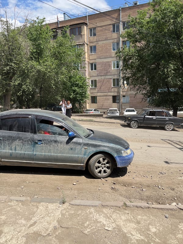 Dusty road traffic on an unpaved street in Gladzor, Armenia