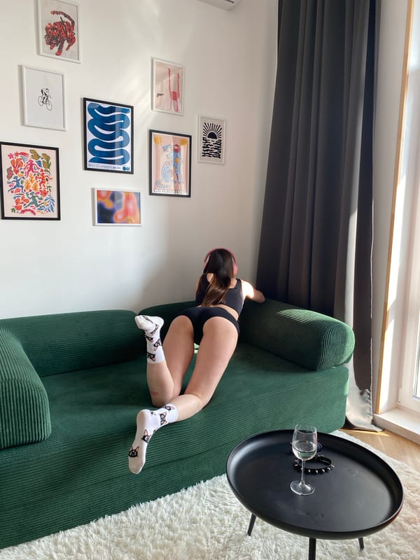 Woman rests on couch wearing headphones and cat socks