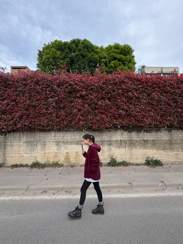 Person in maroon hoodie stands on Milan street