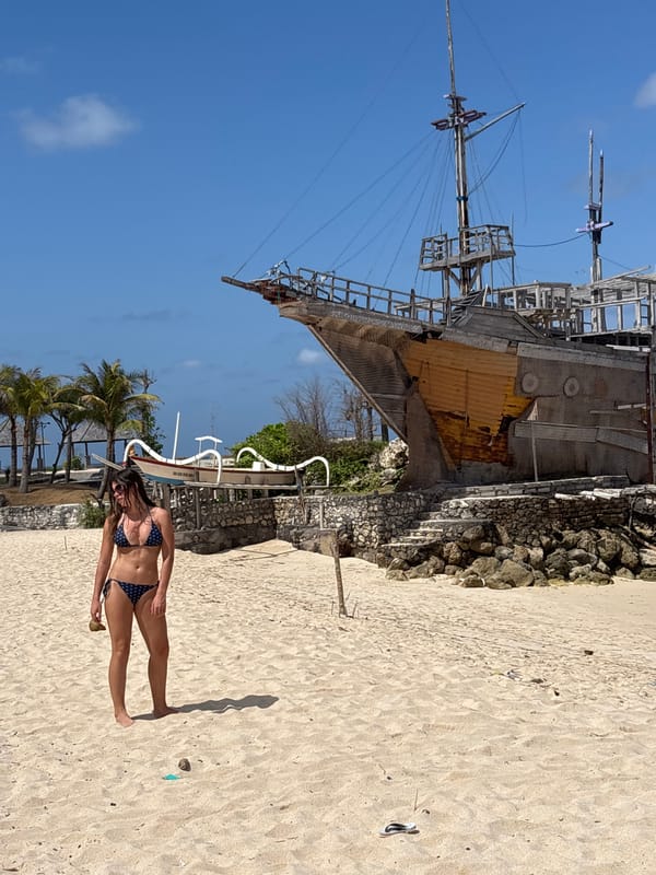 Padang Padang Beach scene: ship installation, sunbathers, Balinese landmarks