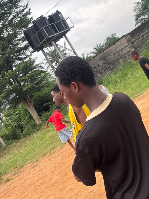 Young men play soccer on dirt field in Nigeria