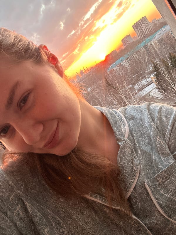 Person takes sunset selfie in pajamas overlooking cityscape