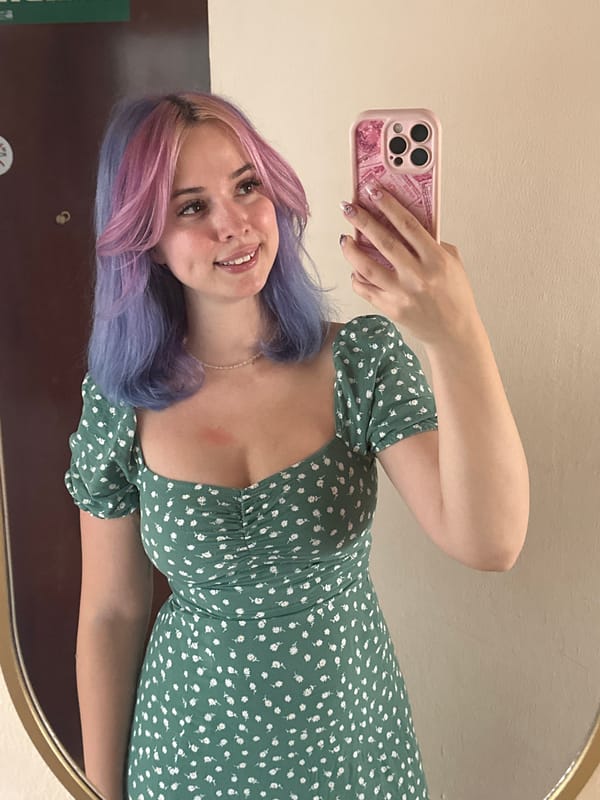 Woman takes mirror selfie in colorful hair, floral dress