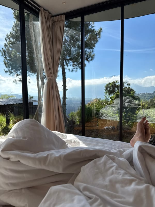 Person in bed gazing through bedroom window in Kintamani