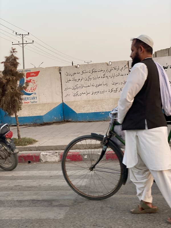 Street life in Kandahar: foot traffic, bikes, and a rickshaw