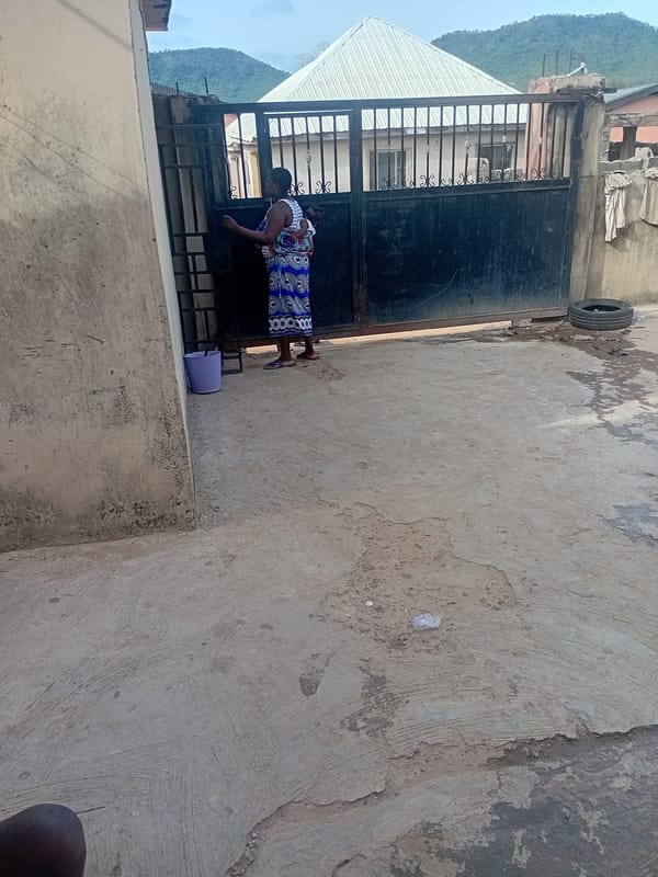 Woman with baby, man with phone near metal gate