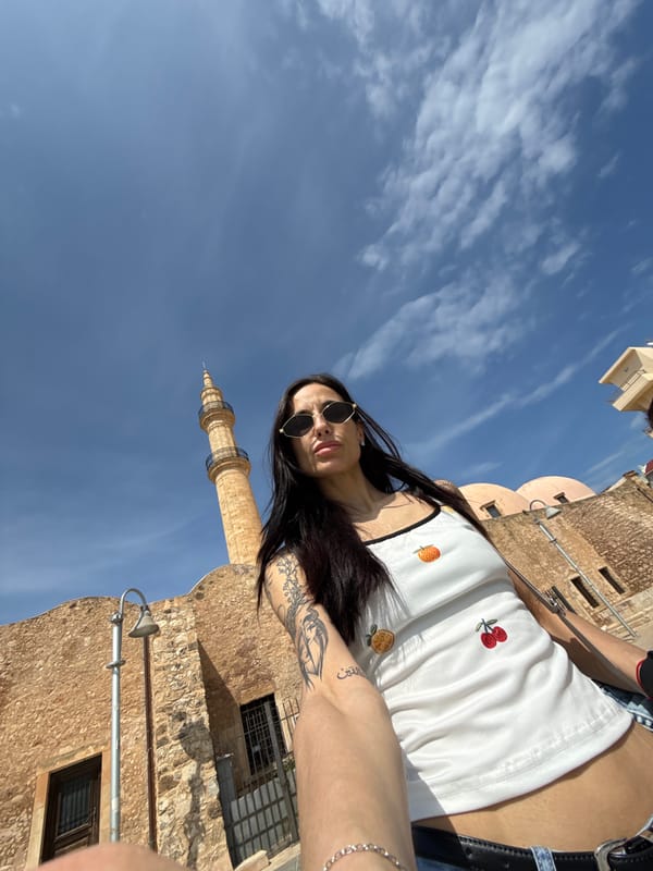 Woman rests near historic Venetian lighthouse in Rethymno waterfront