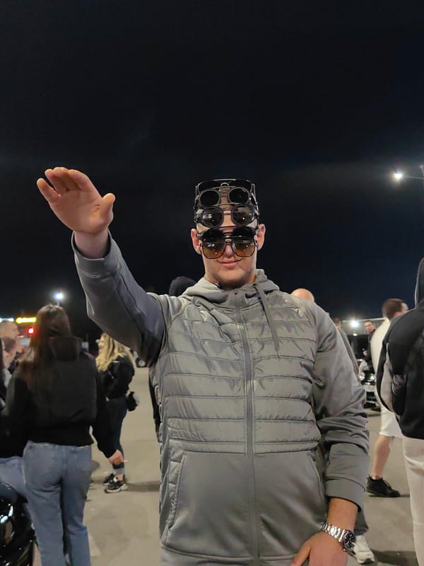 Man poses with three stacked sunglasses in nighttime Sofia