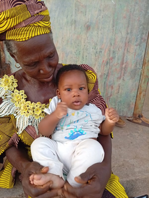 Elderly woman holds baby in traditional dress in Rido