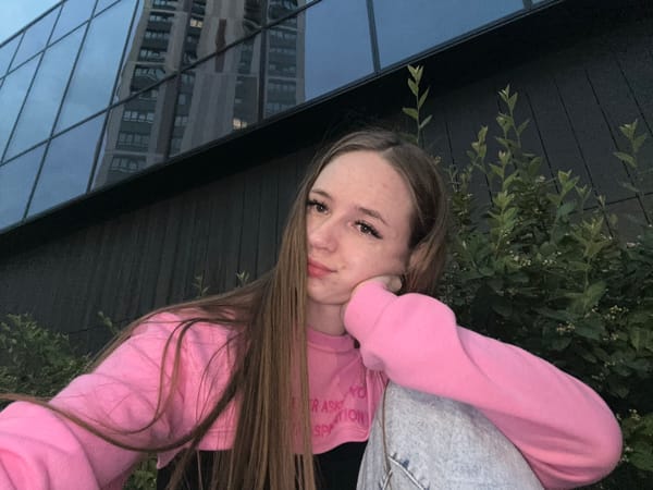 Woman in pink sweatshirt takes multiple selfies around city