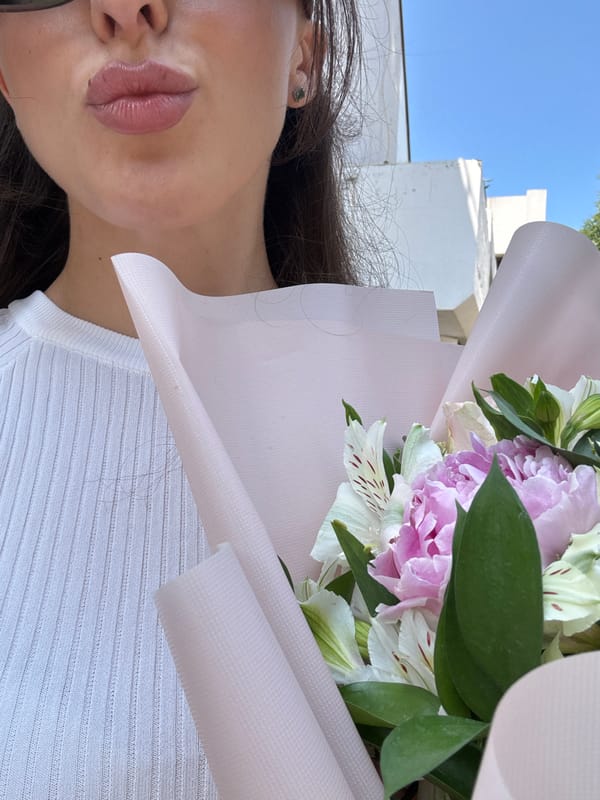 Woman carries flower bouquet through sunny Holon streets