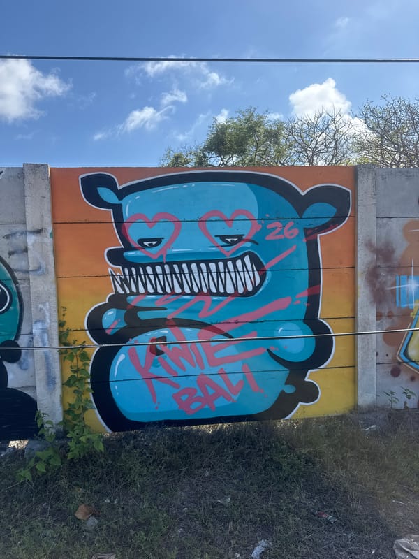 Bali roadside graffiti wall and macaques foraging on scattered fruit