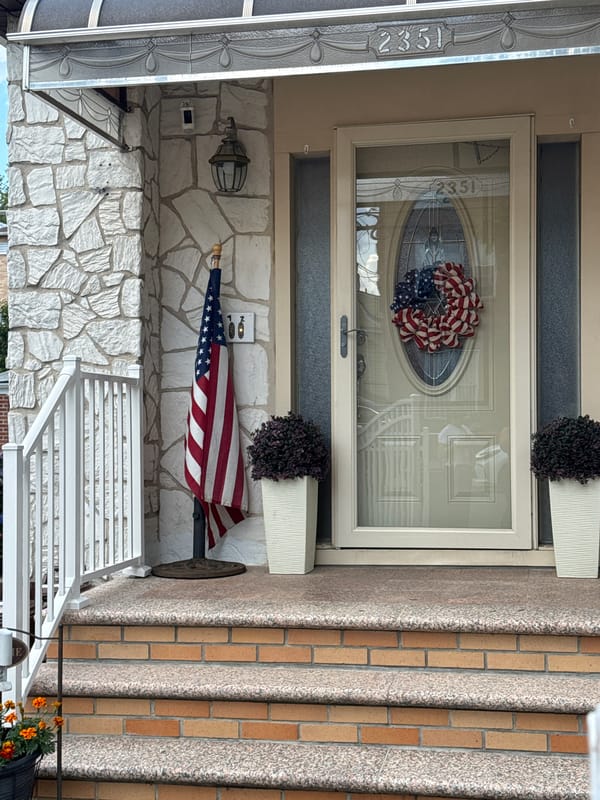 Brick rowhouses, flags, and summer flowers in a NYC neighborhood