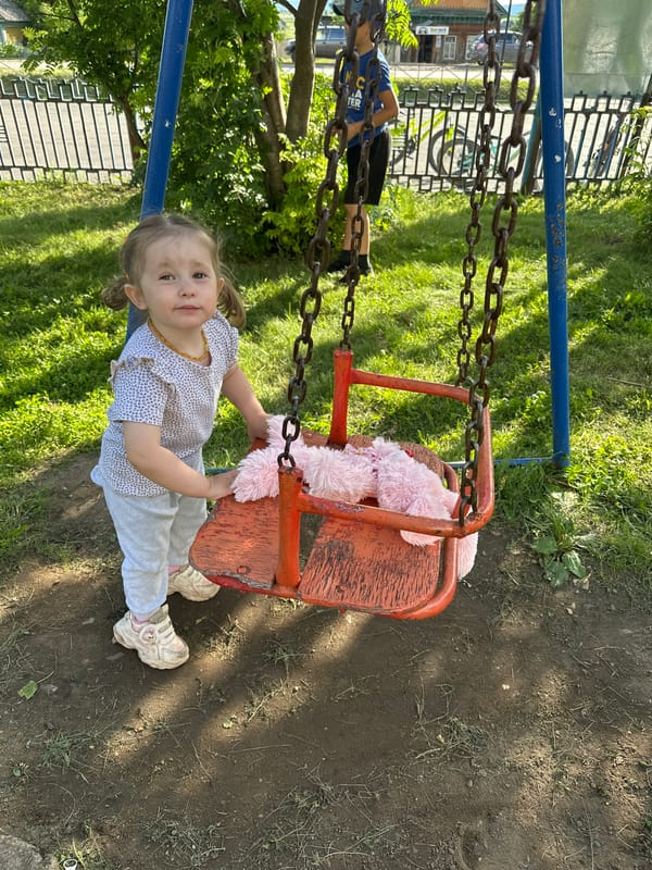 Rusty swing set on a dirt playground in rural Russia