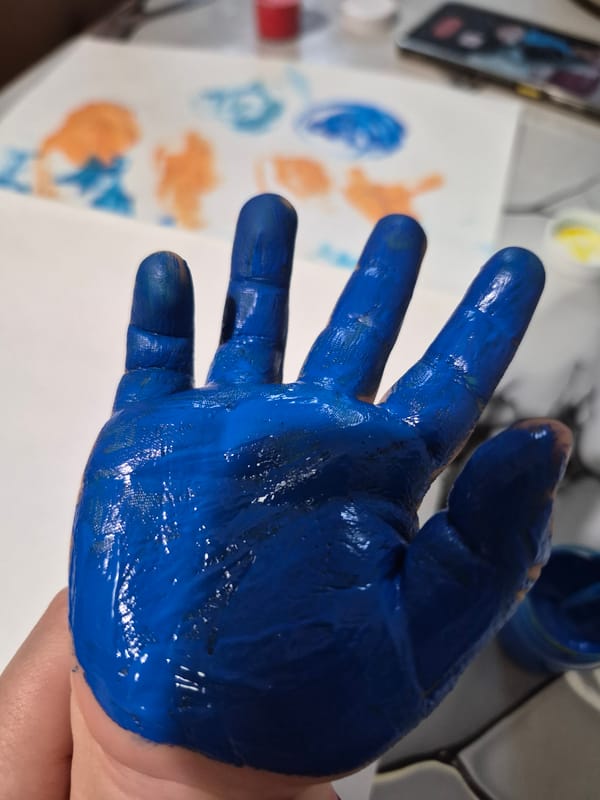 Child creates colorful handprint art in Tobolsk painting session