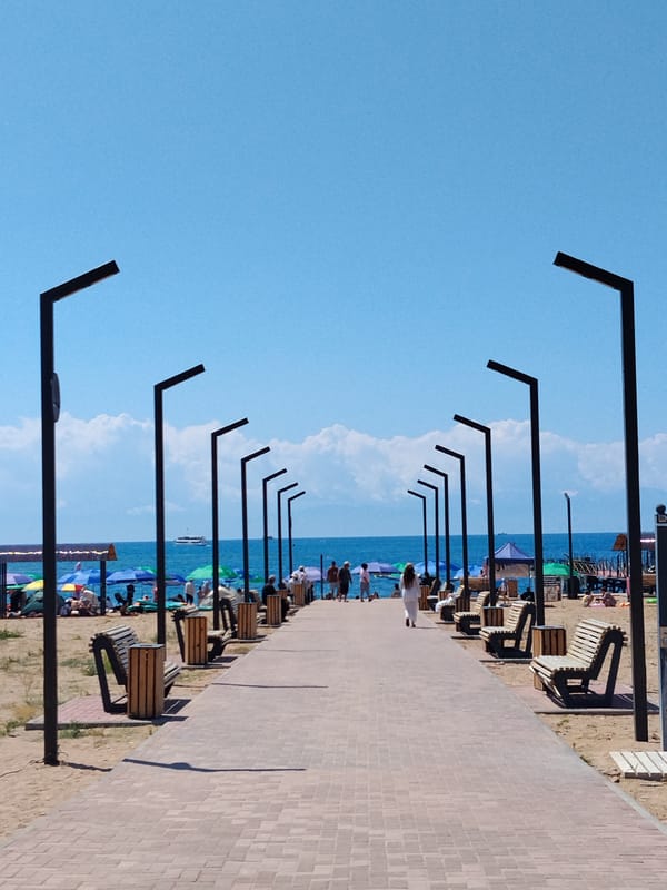 Crowded beach day with waterfront walkway and nearby food stalls