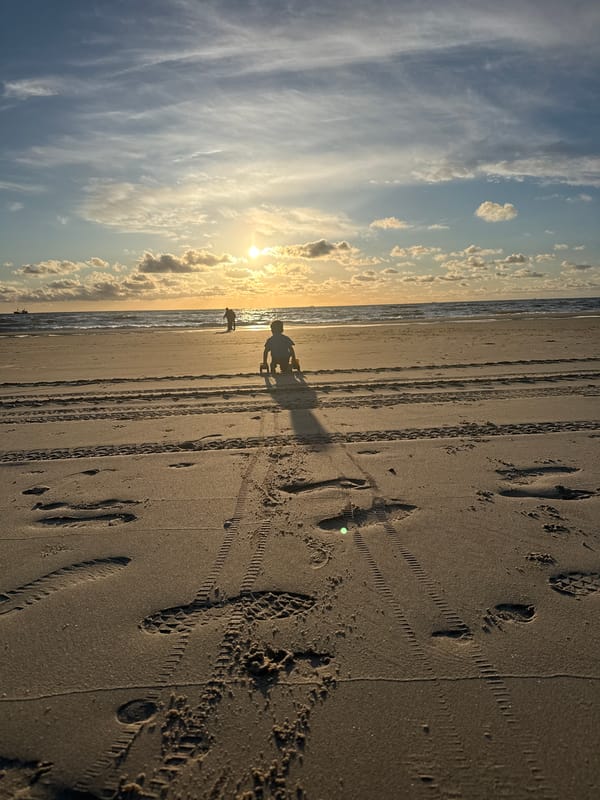 Child plays with toy truck on Petten beach at sunset