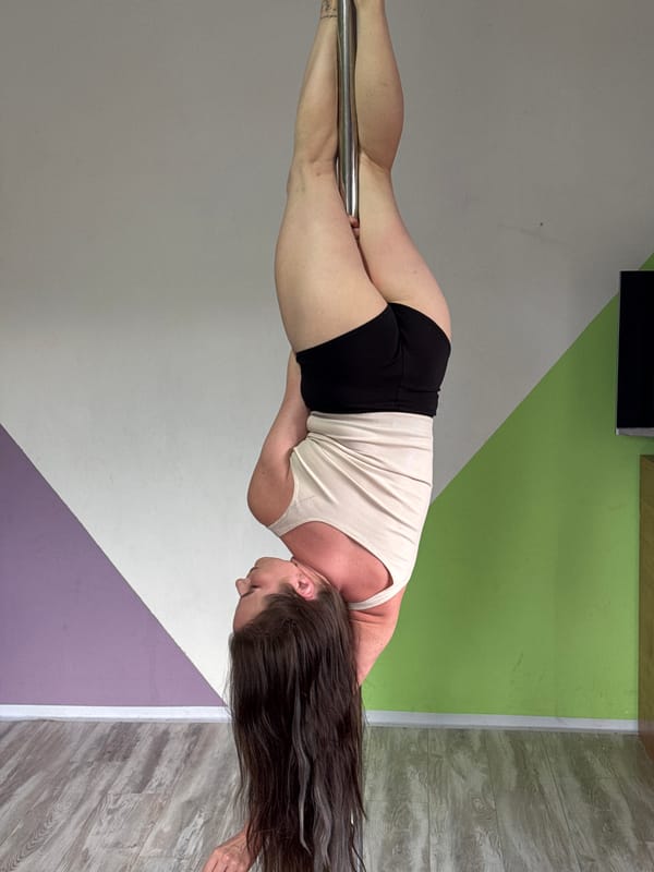 Woman practices pole fitness routine with flowers in Russian studio