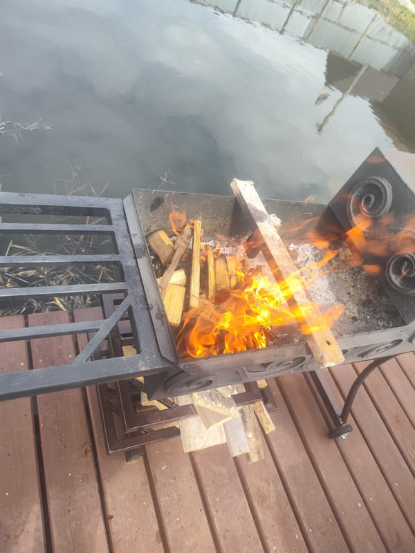 Deck fire burns beside water under dramatic cloudy skies