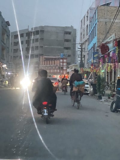 Cyclists and motorcyclists navigate busy Kandahar streets