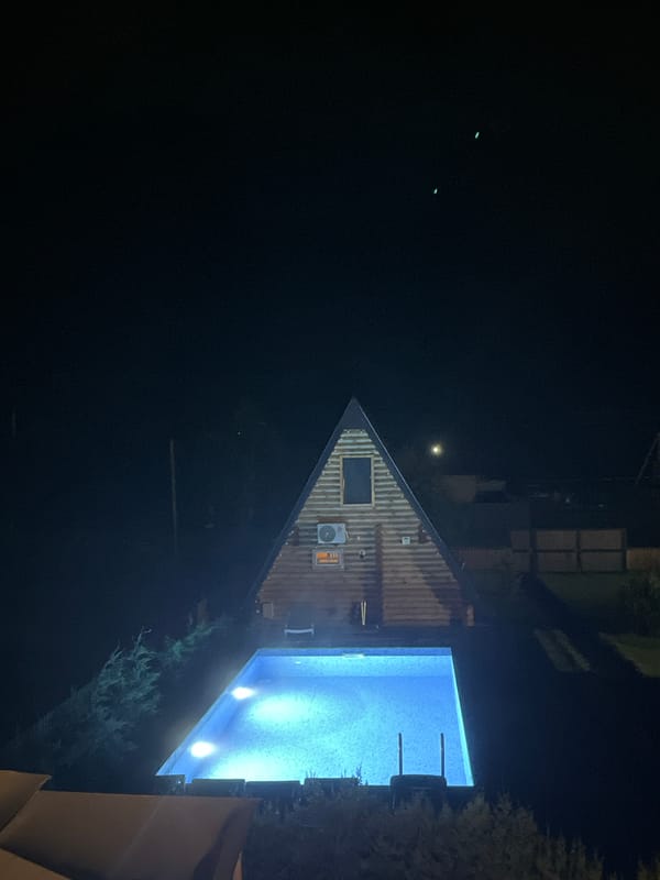 Triangular cabin glows at night beside a blue pool in Georgia