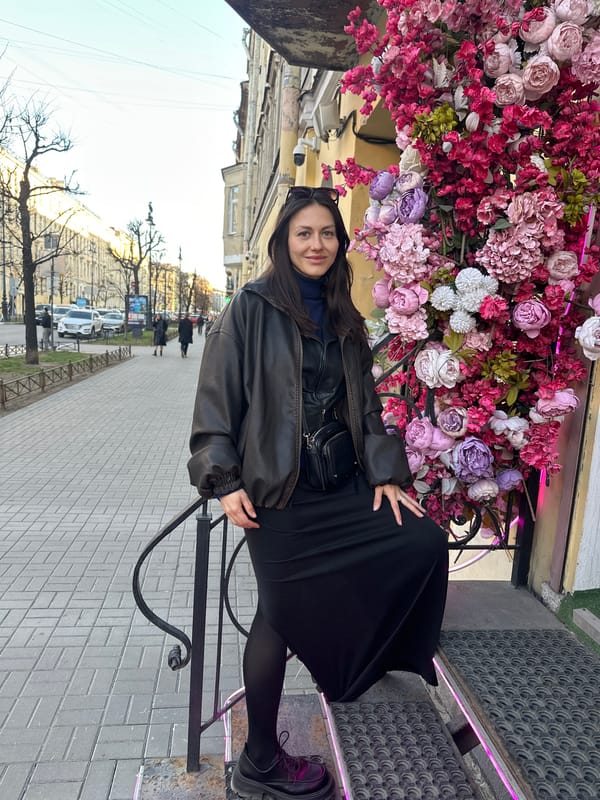 Woman sits by colorful flower display in Saint Petersburg