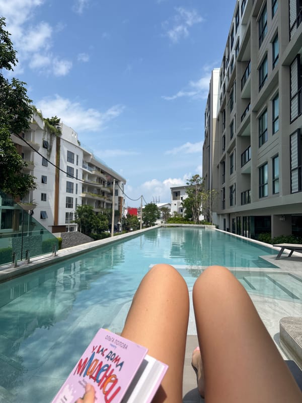 Person reads pink book poolside in Choeng Thale, Thailand
