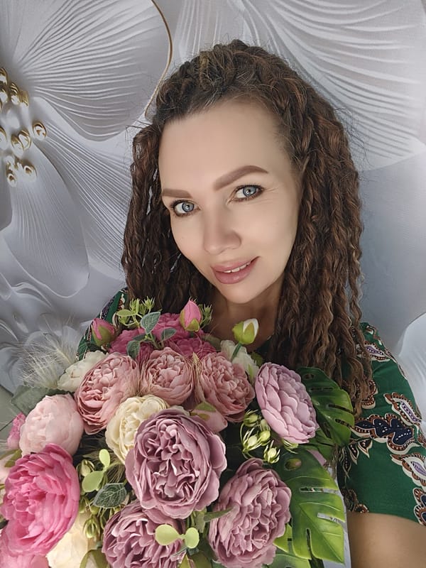 Woman poses with colorful flower bouquet in green dress