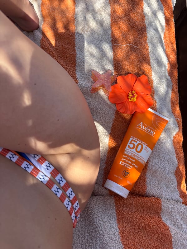 Person sunbathing with Avène sunscreen on decorated beach towel