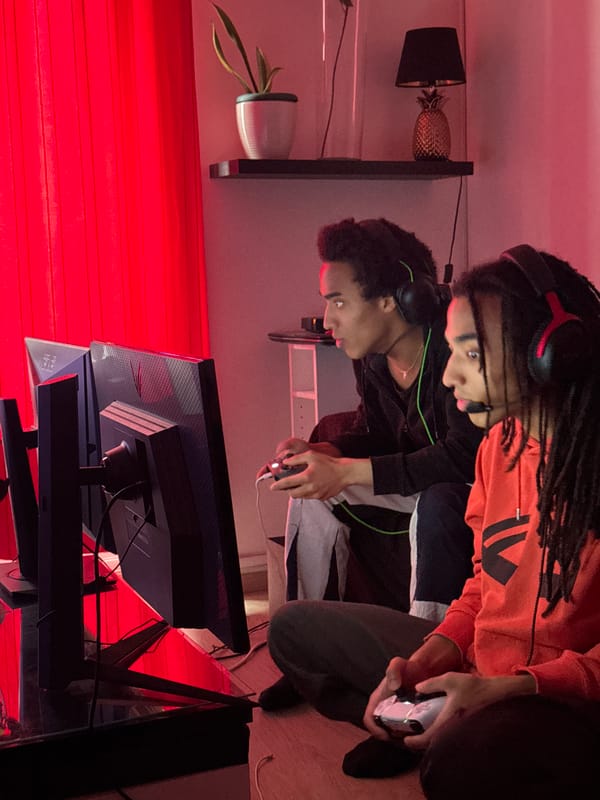 Two friends gaming together in red-lit Paris apartment