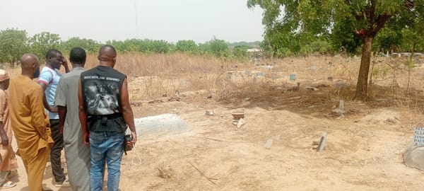 Men in mixed attire gather at city graveyard
