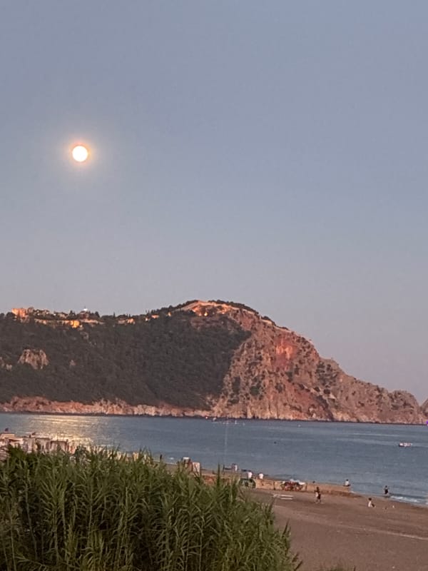 Full moon rises over Alanya's Mediterranean coastline at dusk