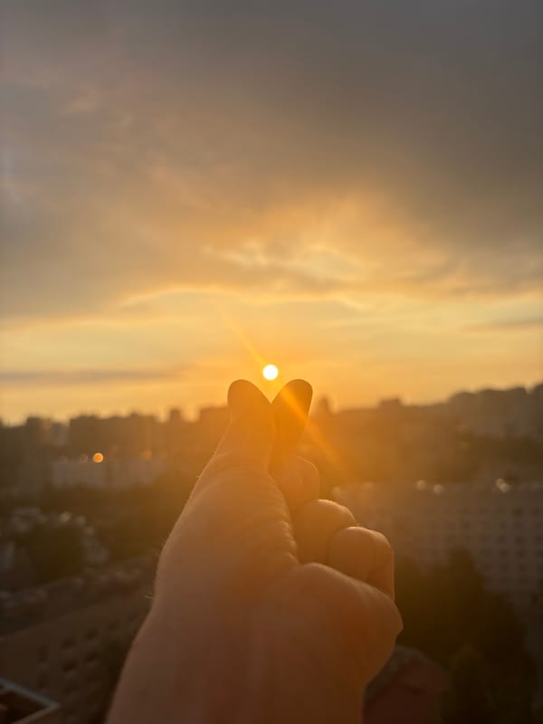 City sunset from above, with hands framing the golden hour