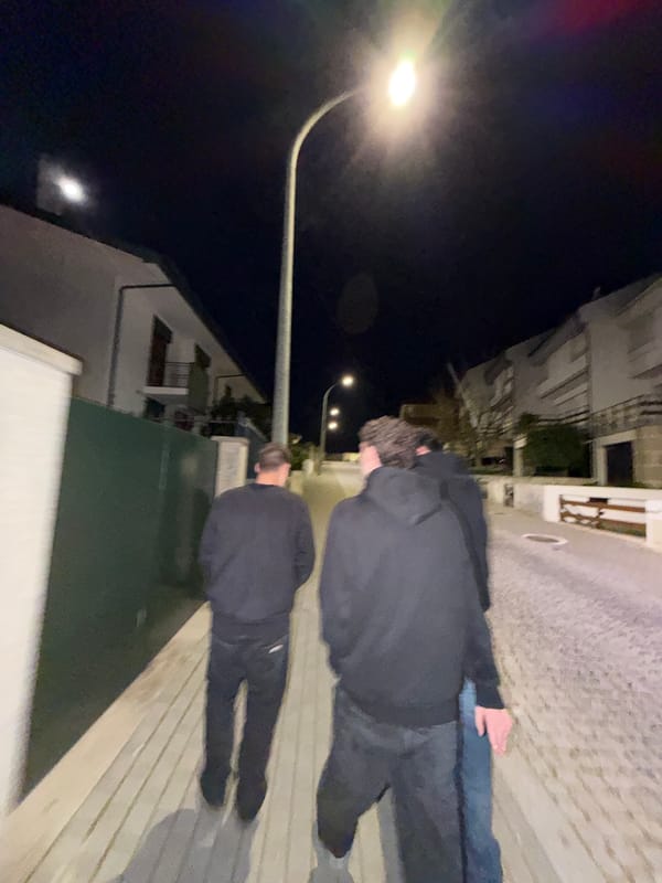 Two people walk illuminated street in Vila Real at night