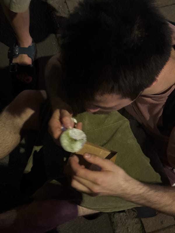 Young man eats outdoors on Milan street Saturday evening