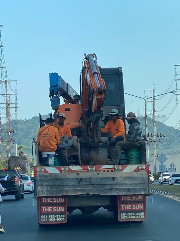 Construction crew travels with excavator on flatbed truck