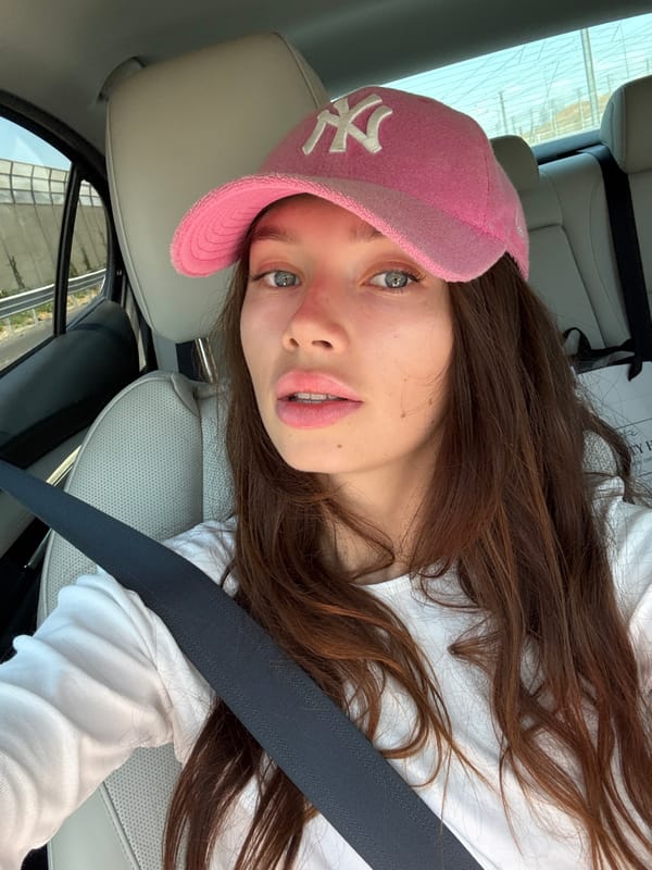 Passenger seat moment in Azor, pink NY cap in frame
