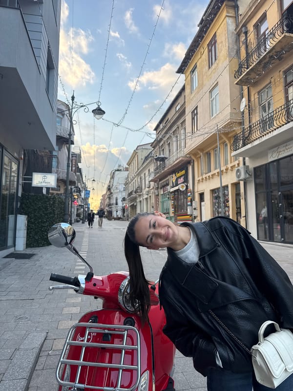 Woman poses with red scooter near Romanian museum