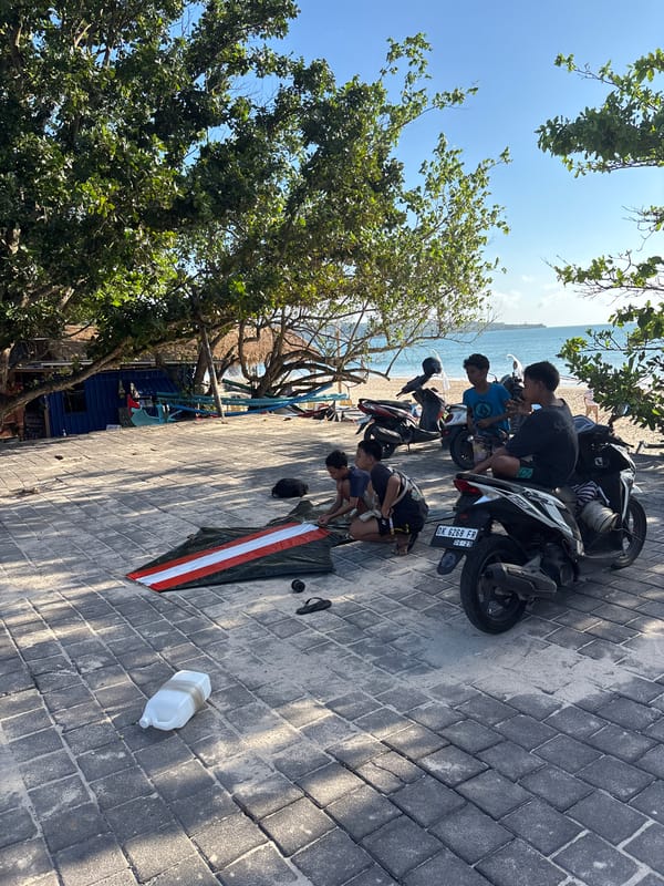 Young men gather on Kuta beach pathway during sunny morning
