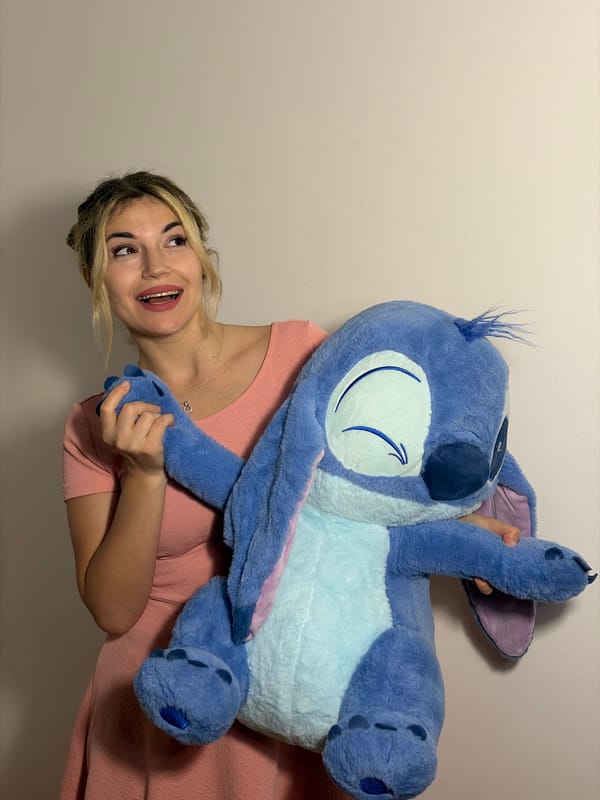 Woman playfully poses with Disney Stitch plush toy in Budva