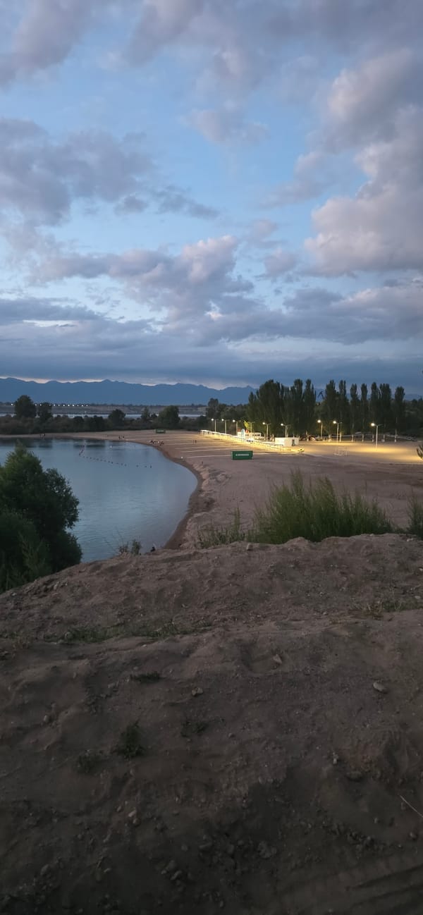 Dusk at a Kyrgyz lakeside beach, mountains on the horizon