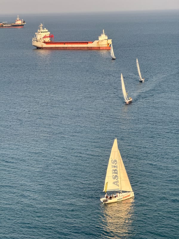 Sailboat race off Limassol with cargo ships passing through
