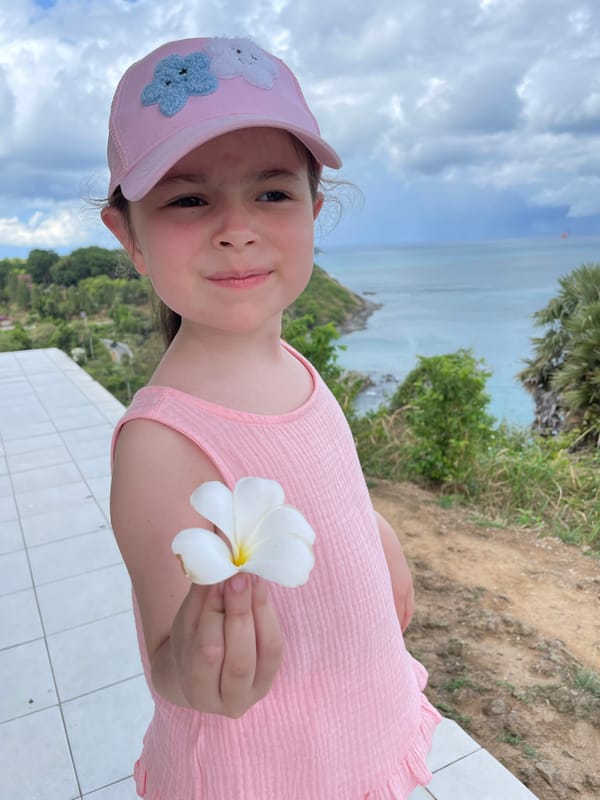 Girl with flower poses at Thailand's scenic Promthep Cape