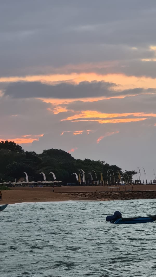 Bali waterfront at dusk, boats moored under a dramatic sunset sky