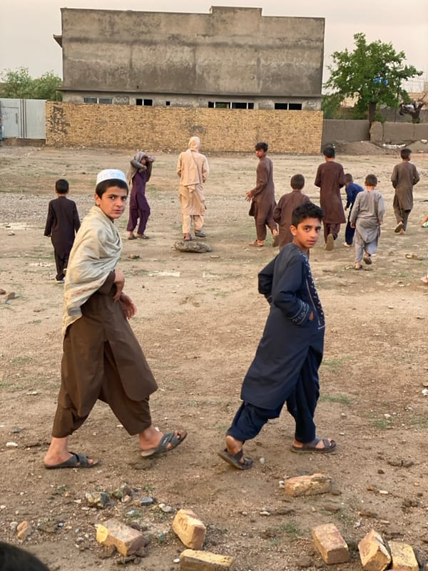 Children play amid construction, rain in Kandahar afternoon